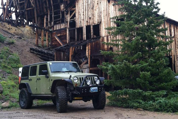 Green Jeep in front of abandoned mine structure