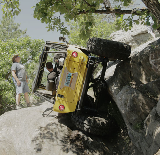 Yellow Jeep rock crawling at an extreme angle