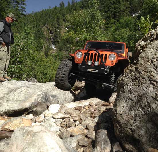 Orange Jeep climbing rocks at the Rock N Woods adventure in the Black Hills of South Dakota.