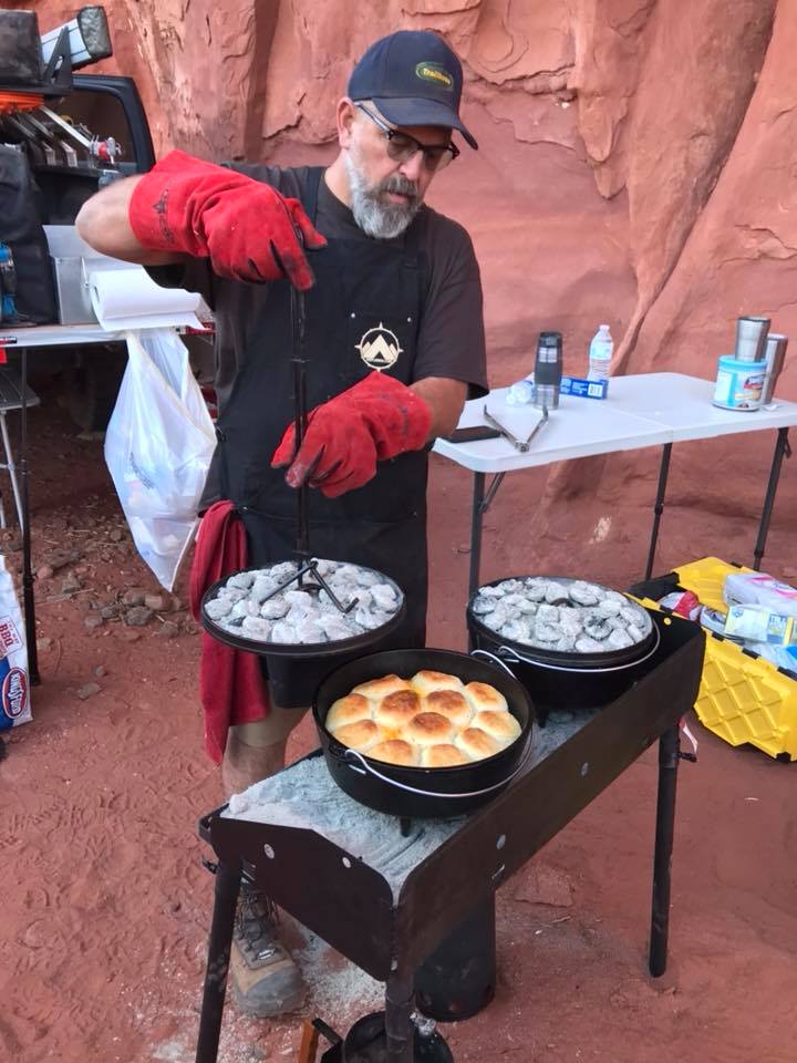 Breakfast biscuits over a five layer egg dish. Bob counts the number of charcoal briquettes both below and on top of the Dutch Ovens for the perfect cooking temperature.